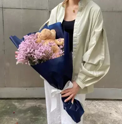 Teddy bear bouquet with pink limonium in navy blue wrap with white ribbon.