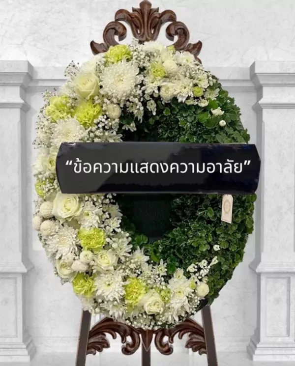 Funeral wreath with white and green flowers and a black ribbon with Thai text.