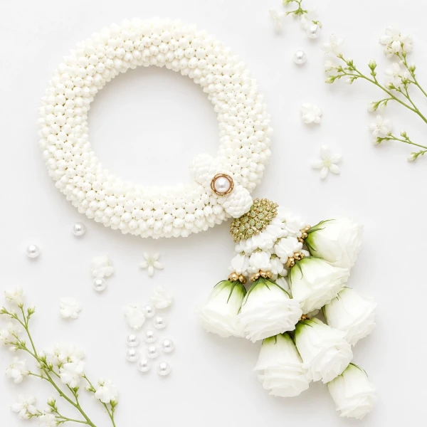 Hand-woven jasmine garland with white roses on a shimmering pink fabric.