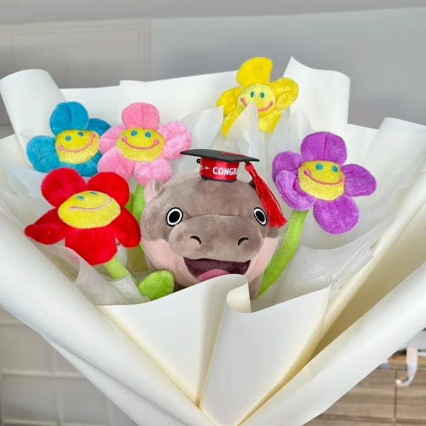 Plush graduation bouquet with a hippo wearing a cap and smiling flower plushies.