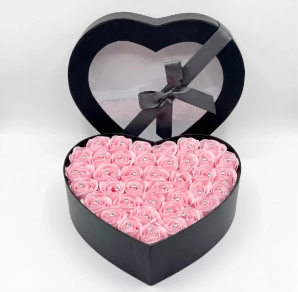 Black heart-shaped box filled with pink roses with diamond centers.