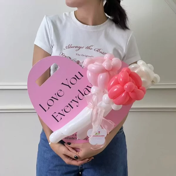 Woman holding heart-shaped balloon arrangement with "Love You Everyday" and triple pink rose balloons.