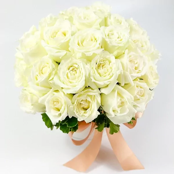 Round white box filled with 25 white roses tied with a peach ribbon.