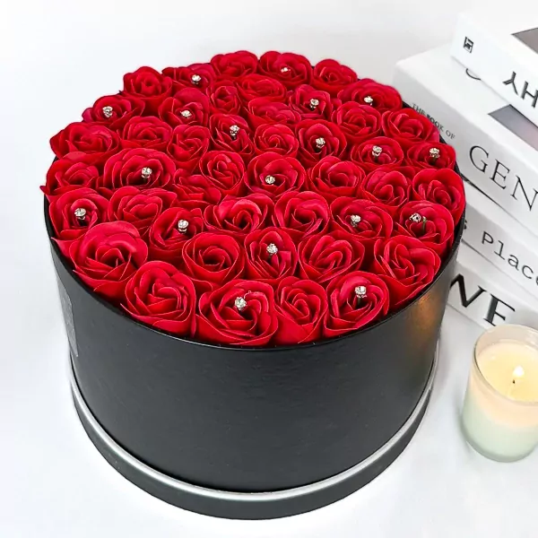 Black round box filled with red roses adorned with diamonds.