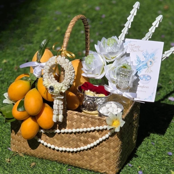 Songkran gift basket with golden fruits, artificial garland, lotus flowers, and a Songkran card.