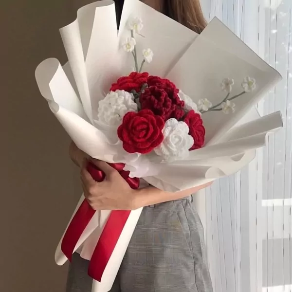 Crocheted bouquet of red and white roses with white accent flowers and red ribbon.