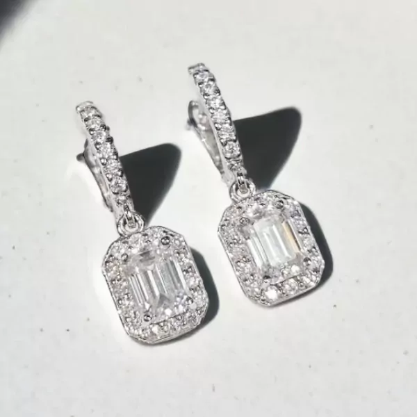 Diamond and moissanite emerald-cut drop earrings, showcasing their sparkle and intricate settings.
