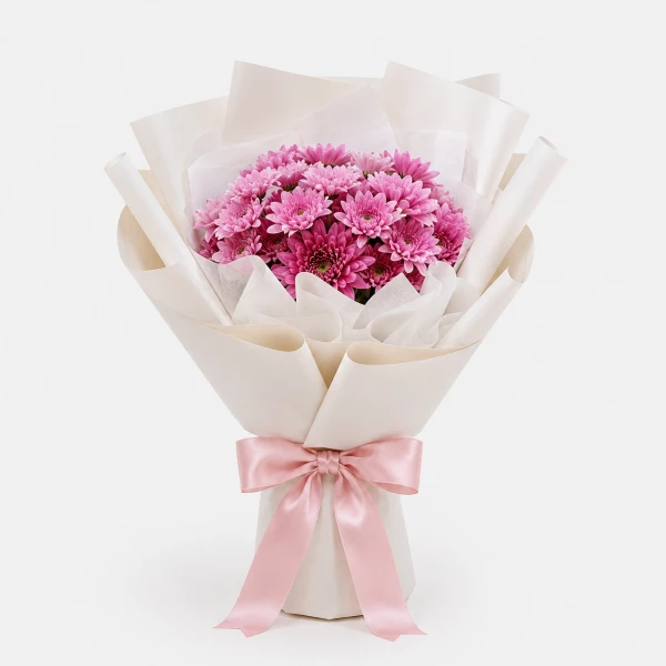 Bouquet of pink mums in white paper with a pink ribbon bow.