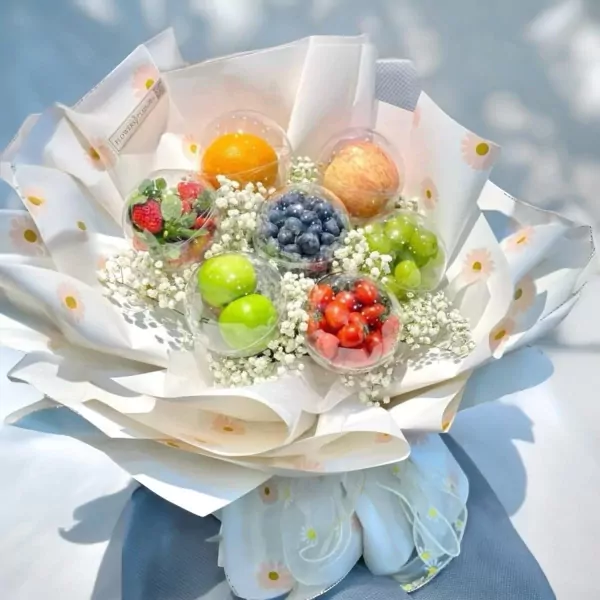 A fruit bouquet with clear spheres of grapes, strawberries, blueberries, apples, and oranges, surrounded by baby's breath.
