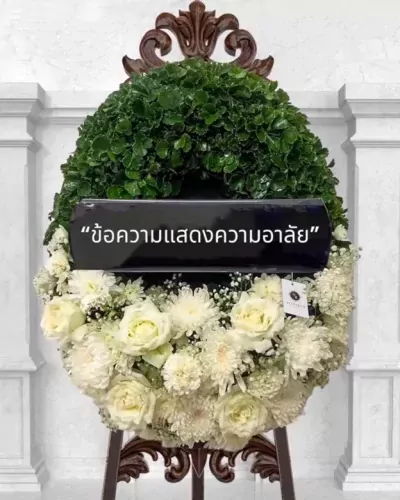 Floral wreath with a black banner and Thai text, featuring white roses and green leaves.