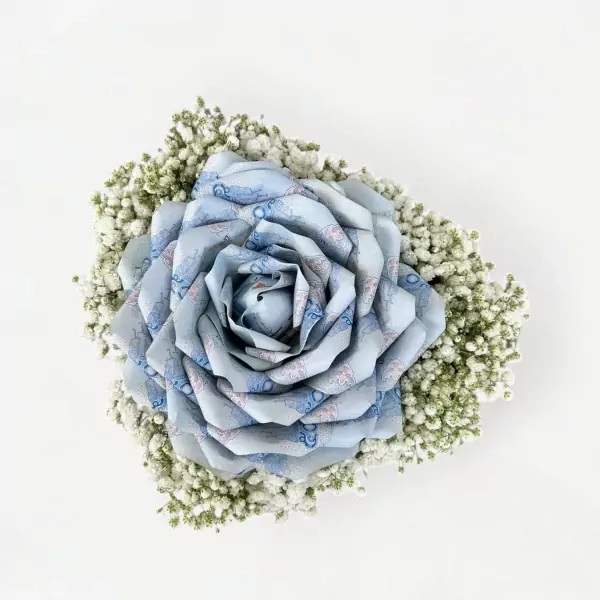 Blue rose made of banknotes in a bouquet of white flowers.