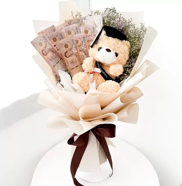 Graduation teddy bear in a bouquet with Thai baht banknotes and a dark brown ribbon.