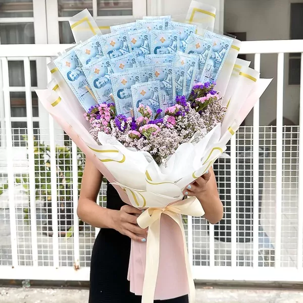 A bouquet of dried flowers with transparent money holders, tied with a peach ribbon.