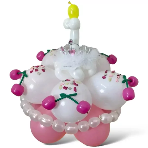 Balloon cake with pink tiara, cherries, and pearl decorations on a white cake stand.