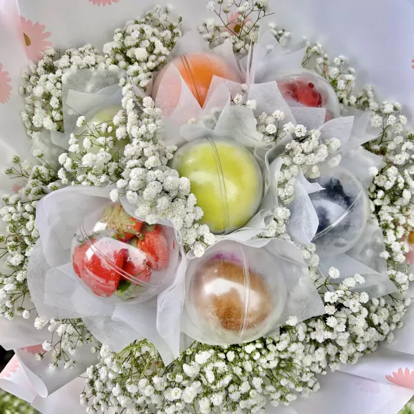 Fruit bouquet in clear spheres with baby's breath, featuring strawberries, grapes, and oranges.