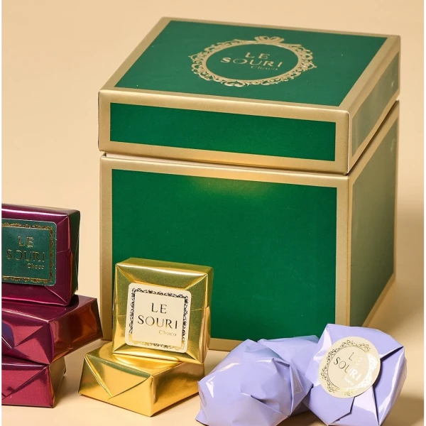 Le Souri Christmas Chocolate Box with gold, maroon, and lavender chocolates and a green and gold gift box.