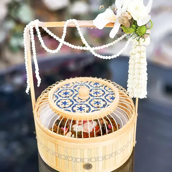 Khao Chae in decorative birdcage-shaped bamboo basket with floral accents.