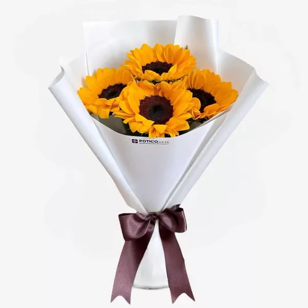 Bouquet of four sunflowers with dark centers and yellow petals, wrapped in white paper and tied with a brown ribbon.