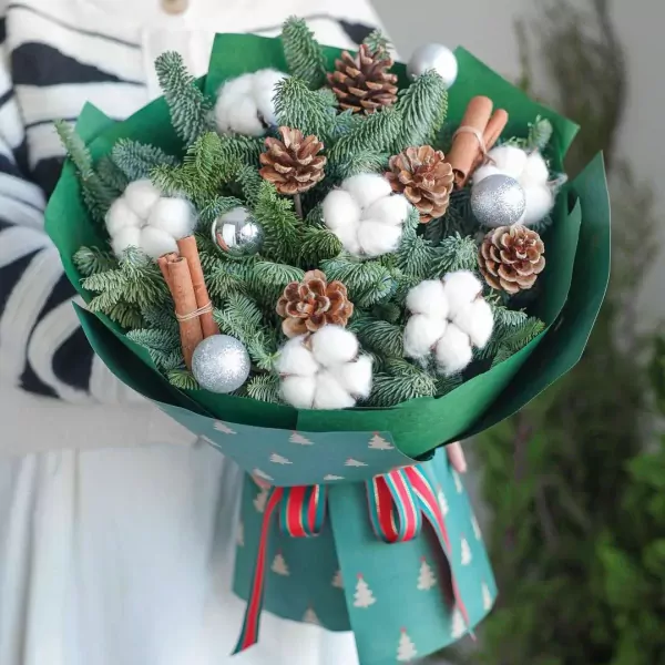 Christmas bouquet with pine branches, cotton, pine cones, cinnamon sticks, and silver ornaments.