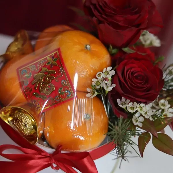 Chinese New Year oranges with red roses and gold ingot, wrapped in clear plastic with a red ribbon.