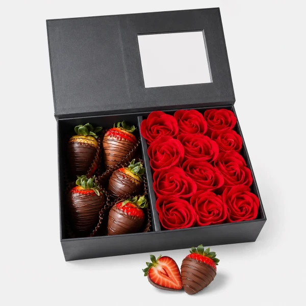 Chocolate-covered strawberries and red artificial roses arranged in a black gift box.