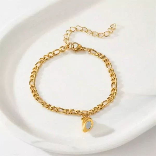 Gold figaro chain bracelet with a gold half-heart pendant containing a blue stone.