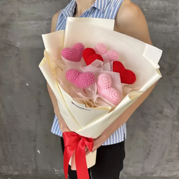 Crocheted heart bouquet in pink and red tones, held by a person.