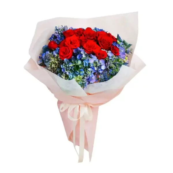 Bouquet of red roses and blue hydrangeas, wrapped in white and pink paper with a cream ribbon.