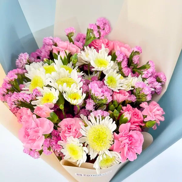 A bouquet of pink carnations, white mums with yellow centers, and small pink statice flowers.