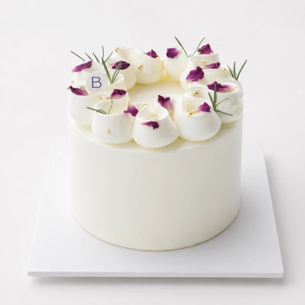 White vanilla cake with piped white frosting, rose petals, and gold pearls.