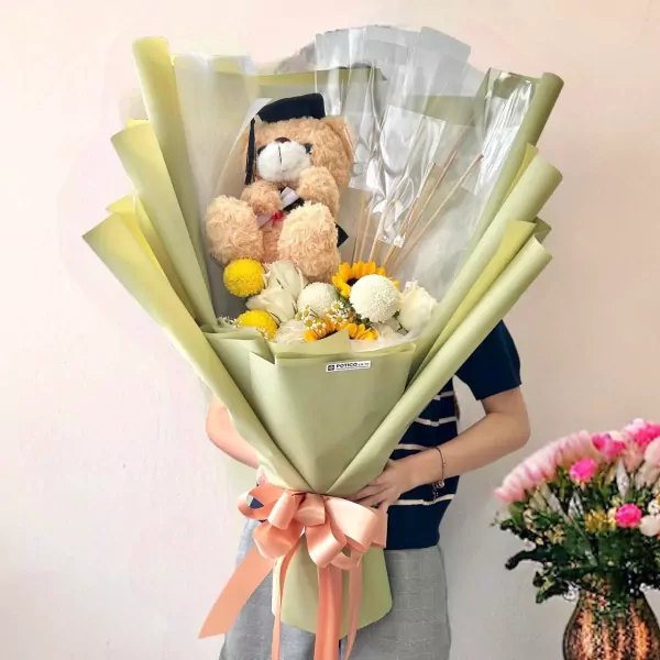 Graduation bouquet with teddy bear, fresh flowers, and money in light green wrapping.