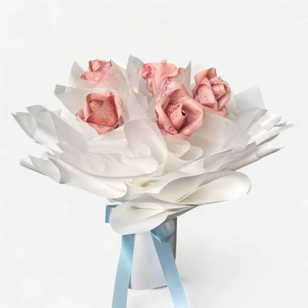 A bouquet of roses made from pink banknotes, wrapped in white tissue paper, tied with light blue ribbon.