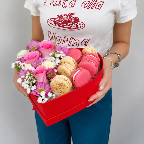 Heart-shaped box with pink roses, purple daisies, white baby's breath, and pink and vanilla macarons.