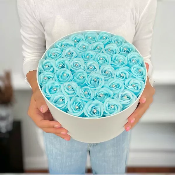 Round white box overflowing with 40 sky blue diamond-studded roses.