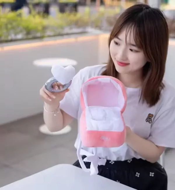 Woman holding a plush pink ring box with a white heart-shaped plush ring cushion.