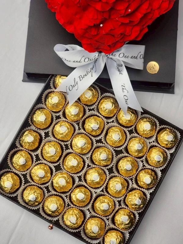 A preserved red rose sits atop a box of Ferrero Rocher chocolates.