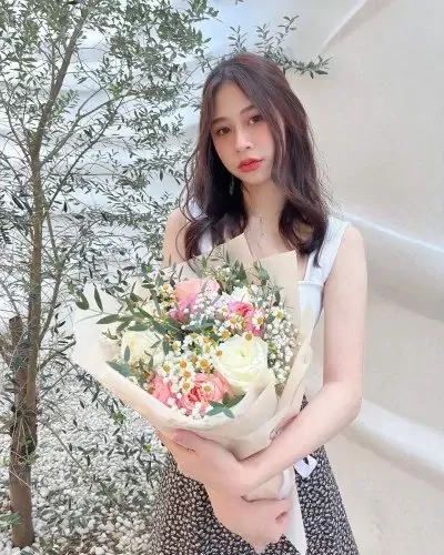 Woman holding a bouquet of pink and white roses, daisies, and baby's breath.