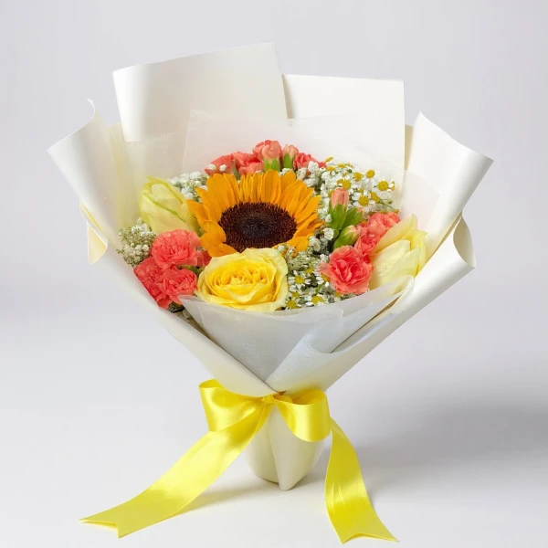 A bouquet of a sunflower, yellow rose, pink carnations, and baby's breath, wrapped in white paper and tied with a yellow ribbon.