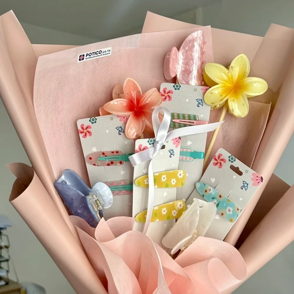 Hair clips with floral designs and butterfly clips arranged in a pink bouquet with paper flowers.