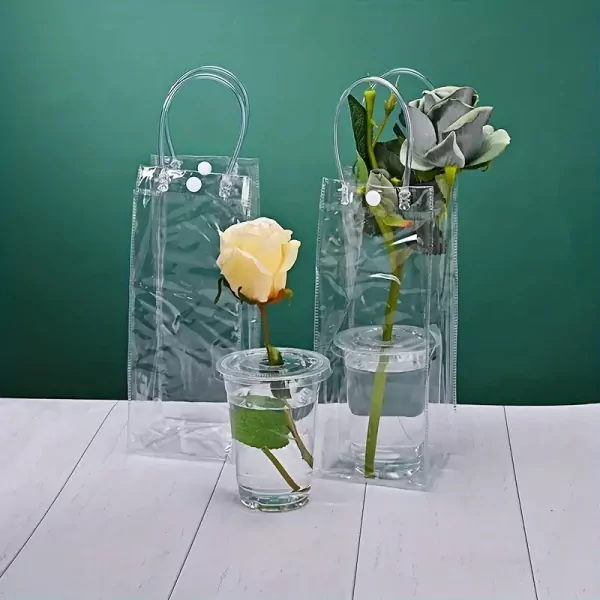 Two clear handbags hold single roses in small cups of water.