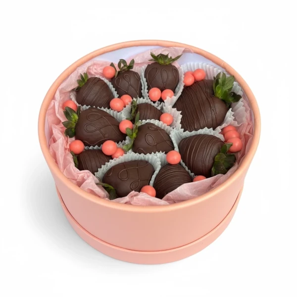 Round pink box with dark chocolate-covered strawberries and pink candy accents.