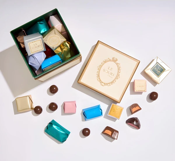 Le Souri chocolates in a gift box and scattered individually on a white surface.