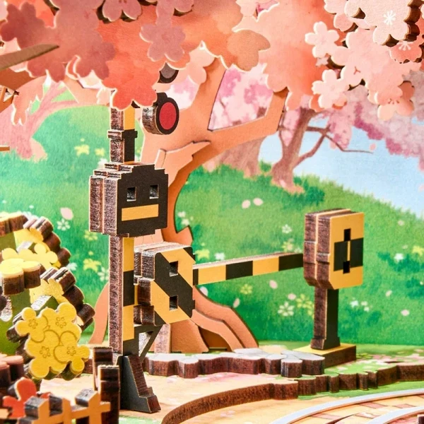 Wooden 3D model of a train crossing with cherry blossoms and a green hillside.
