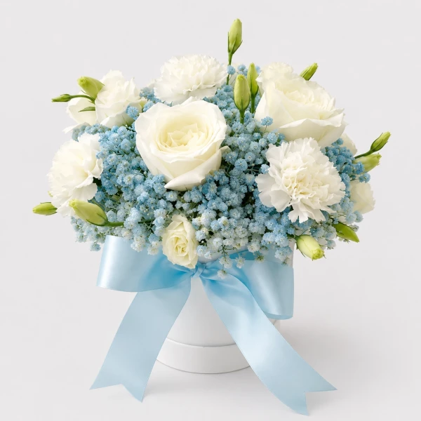 White roses and carnations with blue gypsophila in a white box tied with a blue ribbon.