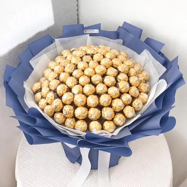 A large bouquet of 100 Ferrero Rocher chocolates, wrapped in dark blue paper with white ribbons.