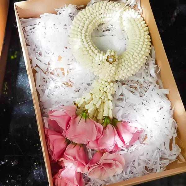A jasmine and rose garland in a gift box, ready for delivery.
