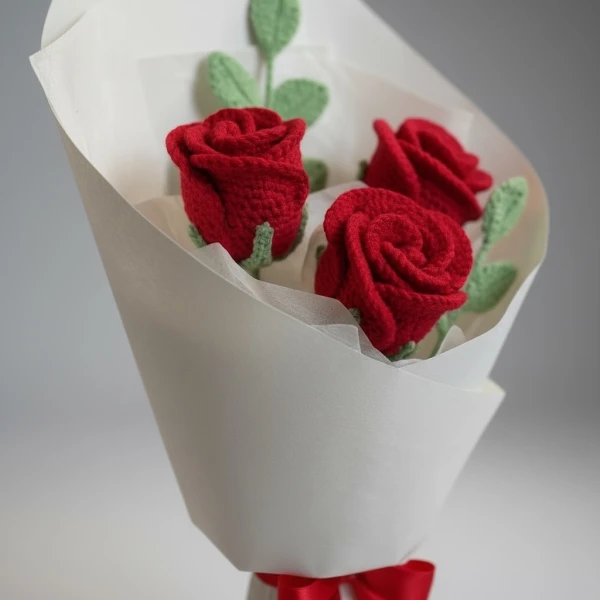 Crocheted red rose bouquet wrapped in white paper, tied with a red ribbon.