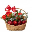 Wicker basket filled with red apples and orange-red roses, adorned with a red bow.