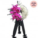 Sympathy wreath with pink orchids, baby's breath, and eucalyptus on a black draped stand.