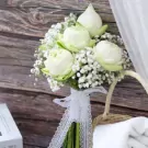 White lotus bridal bouquet with baby's breath and lace ribbon.